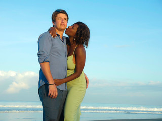  happy and romantic mixed race couple with attractive black African American woman and Caucasian man playing on beach having fun enjoying holidays in multiracial love