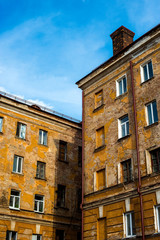 old, yellow, shabby and cracked multi-storey building with a chimney on the roof