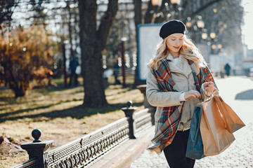 Elegant lady in a winter city. Stylish girl walking with shopping bags. Blonde in a cute beret