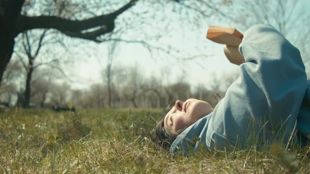 Girl reading in meadow at spring with cat pet. Shot on RED