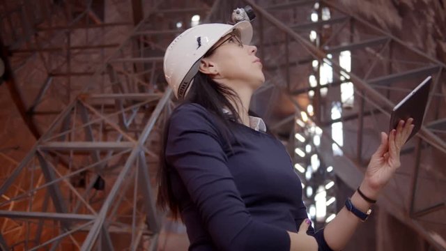 Engineer woman using gadget looking at futuristic construction site. Shot on RED