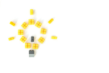 Idea concept. Lamp made of yellow plastic constructor bricks on white background. Popular toys. Copyspace