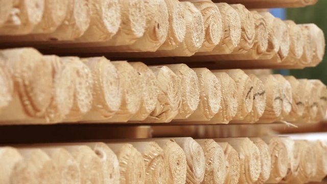 Piles of wooden logs in storage shelves. Round wooden sticks in warehouse