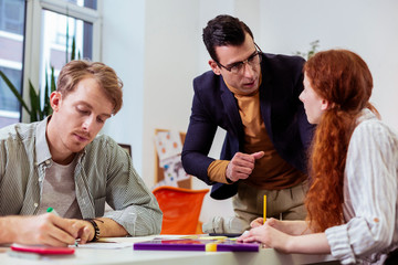 Serious handsome man standing near his students