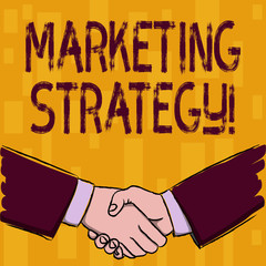 Writing note showing Marketing Strategy. Business concept for plan of action designed to promote and sell a product Businessmen Shaking Hands Form of Greeting and Agreement
