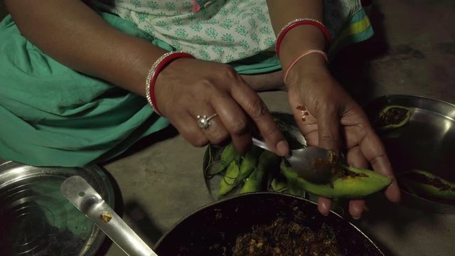 Slow-motion of woman hands preparing, making cooking traditional Indian curry dish with fried Bitter Gourd or Karela, stuffed with vegetable in spicy masala at home kitchen, handheld stabilized 4k 