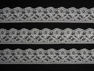 White laces on a black background horizontally - obrazy, fototapety, plakaty