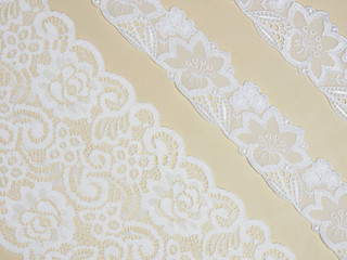 White laces on a beige background diagonally in three row