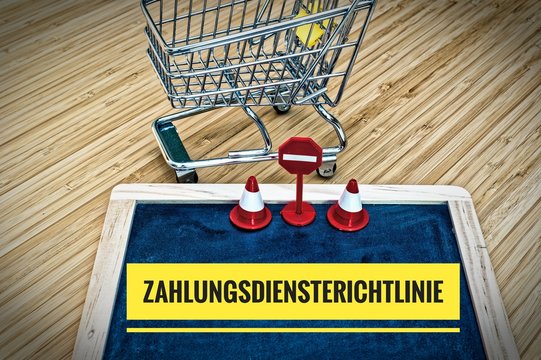 Einkaufswagen und Tafel mit Zahlungsdiensterichtlinie in englisch Geoblocking Regulation