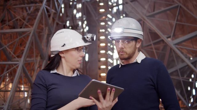 Engineer couple And Client Looking On Project On The Construction Site using tablet in futuristic building, shot in a mine underground