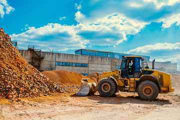 Brick factory equipment, large modern tractor moving bricks, excavator working