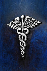 Caduceus, medical symbol in silver color tone mounted to the dark blue leather