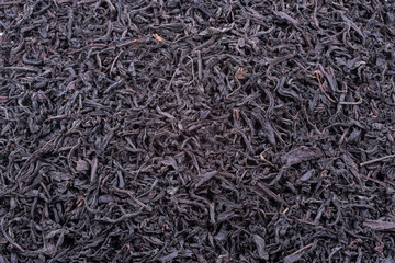 Background of dried tea leaves of dark color. Macro.