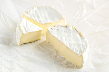 Camembert with piece on white wrapping paper