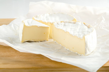 Camembert with piece on white wrapping paper