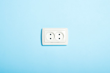 Double white socket on a blue background. Flat lay, top view.