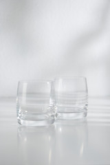 Two empty glasses on white table and white background
