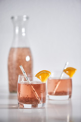 Two glasses and a bottle full of chia water on a table on white background