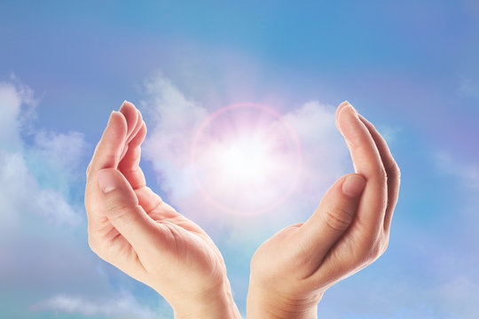 Healing hands with bright sunburst on rainbow background
