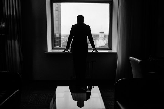 Silhouette view of young businessman is standing in modern office with panoramic windows