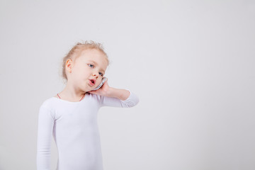 Portrait of the little girl's positive that talking on a cell phone, isolated on white background.