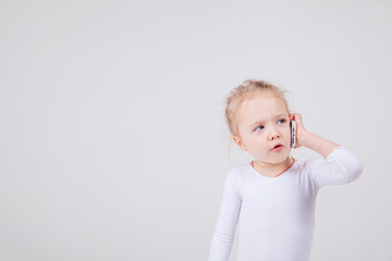 Portrait of the little girl's positive that talking on a cell phone, isolated on white background.