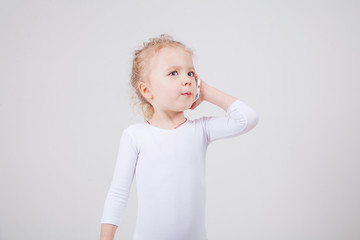 Portrait of the little girl's positive that talking on a cell phone, isolated on white background.