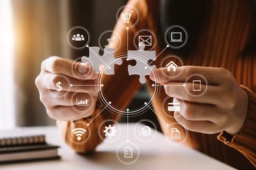 Business solutions and success concept. Businessman hand connecting jigsaw puzzle at office with VR...