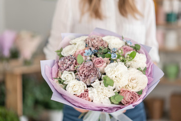 Beautiful bouquet of mixed flowers in woman hand. the work of the florist at a flower shop. Delicate Pastel color. Fresh cut flower. White and lilac color