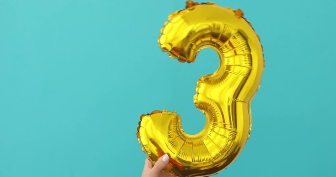Gold foil number 3 celebration balloon on a blue background