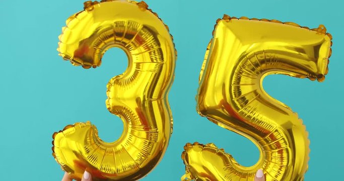 Gold foil number 35 celebration balloon on a blue background