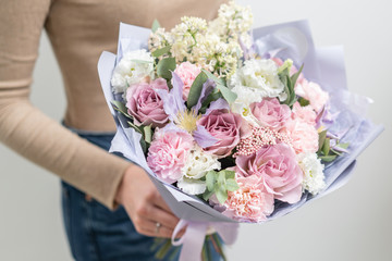 Beautiful bouquet of mixed flowers in woman hand. the work of the florist at a flower shop. Delicate Pastel color. Fresh cut flower. Pink and lilac color