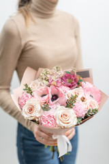 Beautiful bouquet of mixed flowers in woman hand. the work of the florist at a flower shop. Delicate Pastel color. Fresh cut flower. Pink and white color
