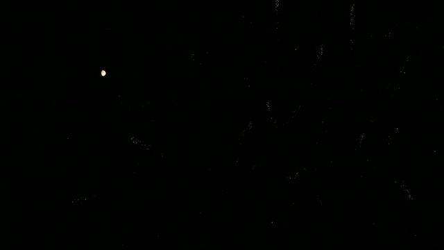 big fireworks explode next to the moon in the night sky