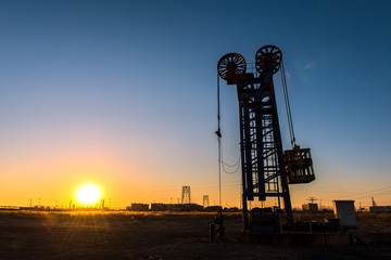 Oil pumps are running in the sunset at the oil field.