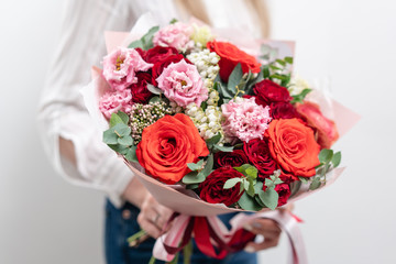 Beautiful bouquet of mixed flowers in womans hands. the work of the florist at a flower shop. Delicate Pastel color. Fresh cut flower. Red and pink color
