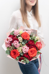 Beautiful bouquet of mixed flowers in womans hands. the work of the florist at a flower shop. Delicate Pastel color. Fresh cut flower. Red and pink color