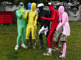 Group of friends at music festival in bright various coloured lycra body suits posing for a...