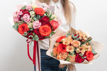 two Beautiful bouquets of mixed flowers in womans hands. the work of the florist at a flower shop. Delicate Pastel color. Fresh cut flower. Red and peach color