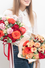 two Beautiful bouquets of mixed flowers in womans hands. the work of the florist at a flower shop. Delicate Pastel color. Fresh cut flower. Red and peach color