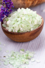 Sea salt in bowl, aroma oil in bottles, Wellness and flowers on grey textured background and flowers on vintage wooden background. Selective focus.