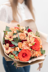 Beautiful bouquet of mixed flowers in womans hands. the work of the florist at a flower shop. Delicate Pastel color. Fresh cut flower. Red and peach color
