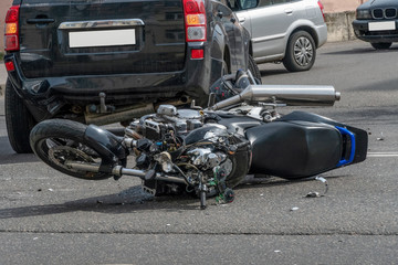 broken motorcycle closeup beside the car. an accident on the road in the city on a sunny day...