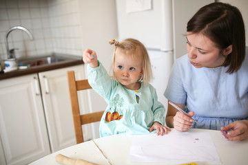 Mom and cute blonde girl in dresses paint together