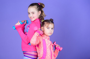 Sport exercises for kids. Healthy upbringing. Sporty babies. Following her sister. Girls cute kid exercising with dumbbells. Motivation and sport example concept. Toddler repeat exercise after sister