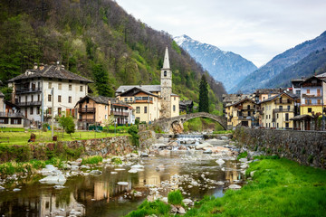 Fototapeta na wymiar Fontainemore alpine village on the Lys river in a forest in the valley of Gressoney near Monte Rosa during spring