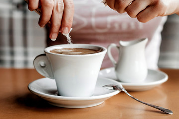 Morning coffee. Closeup of women's hands with coffee cup in a cafe. Female hands holding cups of coffee on a wooden table background in a cafe, vintage color tone
