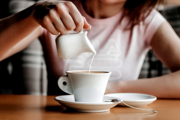 Morning coffee. Closeup of women's hands with coffee cup in a cafe. Female hands holding cups of coffee on a wooden table background in a cafe, vintage color tone