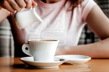 Morning coffee. Closeup of women's hands with coffee cup in a cafe. Female hands holding cups of coffee on a wooden table background in a cafe, vintage color tone