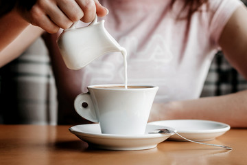 Morning coffee. Closeup of women's hands with coffee cup in a cafe. Female hands holding cups of coffee on a wooden table background in a cafe, vintage color tone